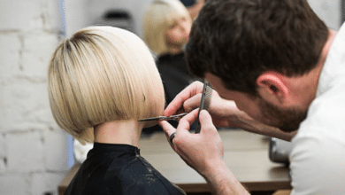 Parrucchiere taglia i capelli a una donna con il caschetto biondo