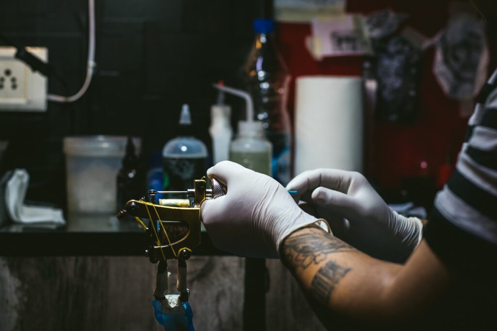 Tatuatore con guanti bianchi che cambia cartuccia a una macchinetta