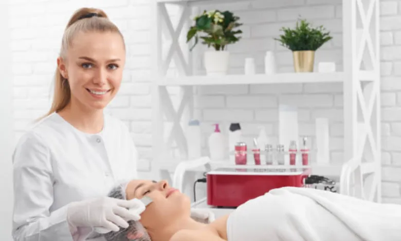 Estetista sorride mentre applica una crema su una cliente sdraiata sul lettino