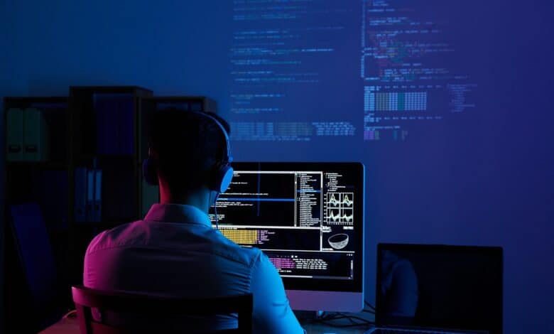 programmatore informatico lavora al computer in una stanza con luce blu
