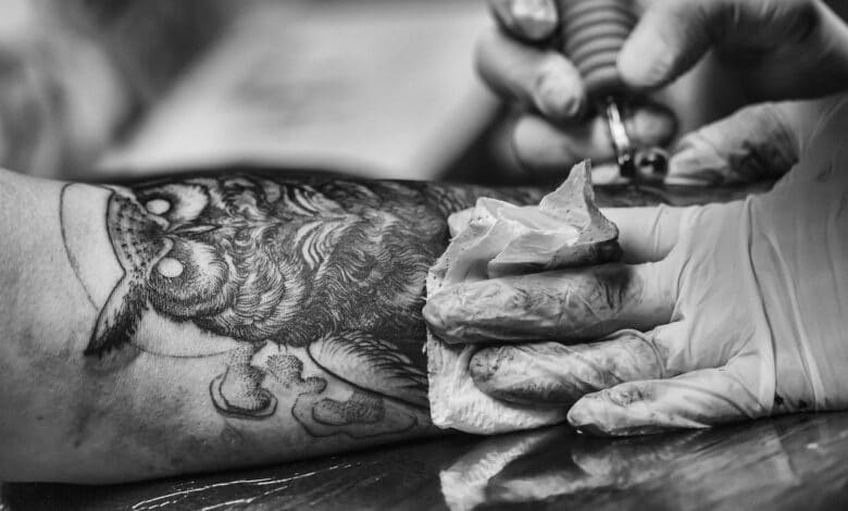 Tatuatore disegna un gufo sul braccio di un cliente